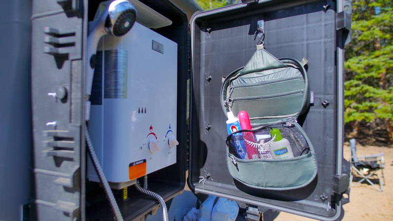 Opened shower section of a Boreas Campers trailer: shower tank, head, and portable shower kit